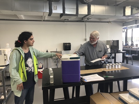 Lucas Forman handing off samples to a scientist at the Berkshire Community College lab.